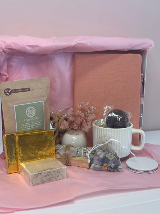 Gift Hamper for wellness including a mug, hot chocolate bomb, chocolate bars, drinking chocolate, chocolate pretzels, a journal and pen, Sage Stick, Palo Santo & Raw Crystal, crystal bag, crystal tree, compact round mirror